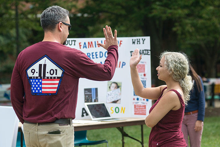 Man in 9/11 commemorative shirt high-fives a Mason student